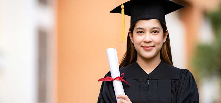 woman stares front wearing mortarboard and holding college diploma