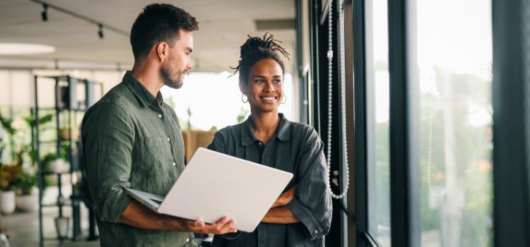 two information technology managers stand in an office talking business